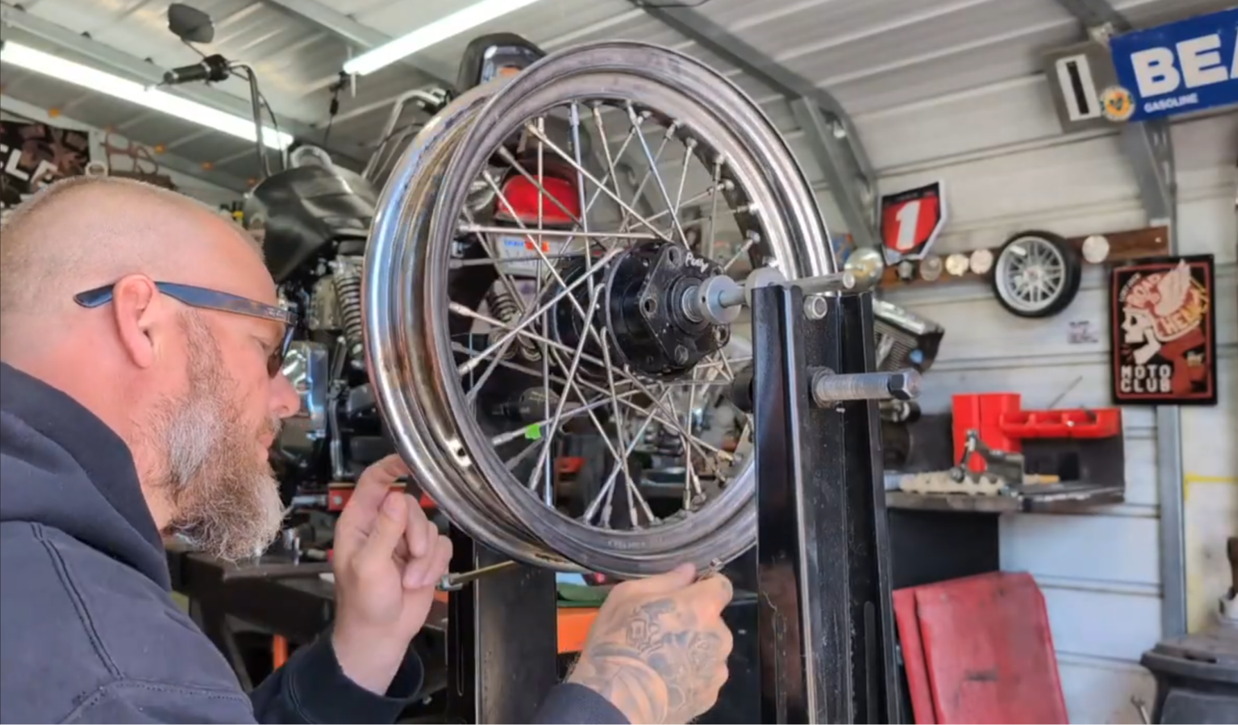 Person working on a motorcycle wheel inside a garage.