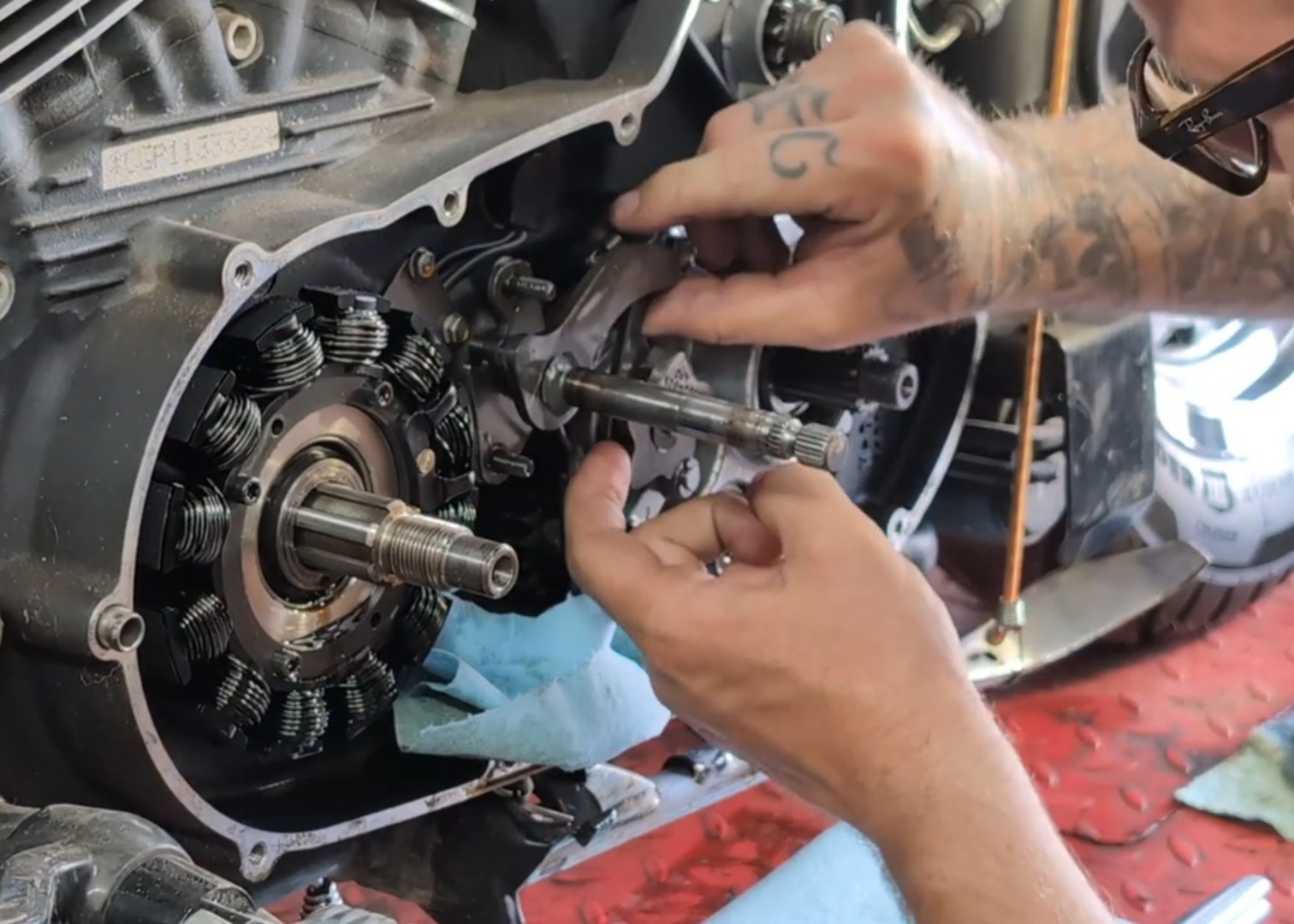 Person working on a mechanical component with tools on motorcycle lift